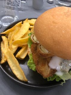 a sandwich and french fries on a black plate