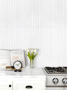 a white kitchen with an oven, stove and flowers