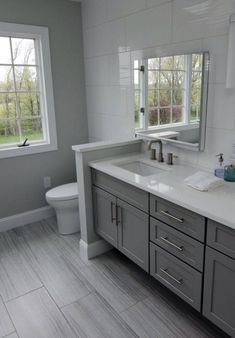 a bathroom with two sinks, a toilet and a large mirror in it's corner