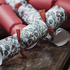 rolled up wrapping paper sitting on top of a wooden table next to some red boxes