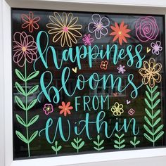 a window with the words happiness blooms from within painted on it in bright colors and flowers