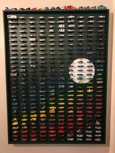 a large display of toy cars on a wall in front of a white circle and black background