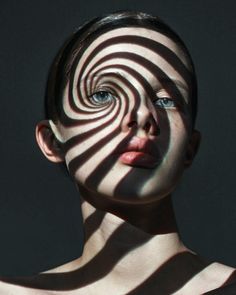 a woman's face with the shadow of a spiral on her body