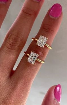 two rings on the finger of a woman with pink nail polish and one ring has a baguette cut diamond