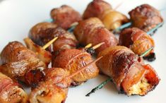 bacon wrapped skewers are sitting on a white plate