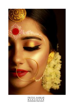 a woman wearing gold and red makeup with flowers in her hair is looking at the camera