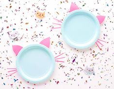 two blue plates with cat ears on them surrounded by confetti