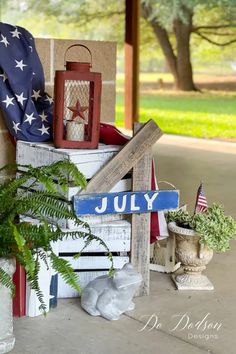 an american flag and other patriotic items sit on a porch next to a potted plant