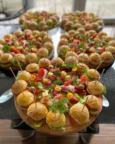 many small sandwiches with toothpicks in them are on a table next to each other