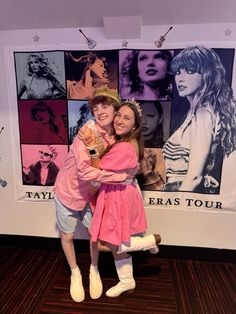 two girls hugging each other in front of a poster