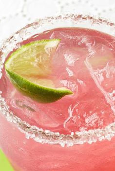 a close up of a drink in a glass with a lime slice on the rim