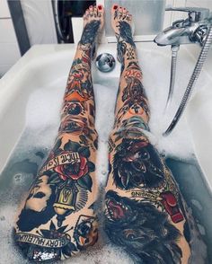 a person has tattoos on their legs and feet in the bathtub with soapy water