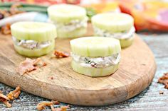 cucumber sandwiches with bacon and cream cheese on a wooden cutting board next to other food items