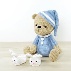 a crocheted teddy bear sitting on top of a wooden table next to two white shoes