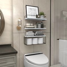 a white toilet sitting in a bathroom next to a sink and a shower stall with shelves on the wall