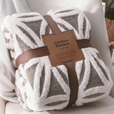 two folded towels sitting on top of a white chair next to a brown label that says comfort blanket