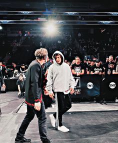 two young men walking across a stage in front of a group of people with microphones