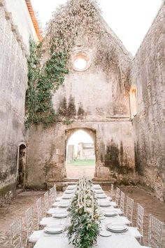 a long table with white chairs is set up in an old stone walled building for a formal function