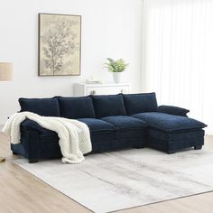 a living room with a blue sectional couch and white rugs on the hardwood floor