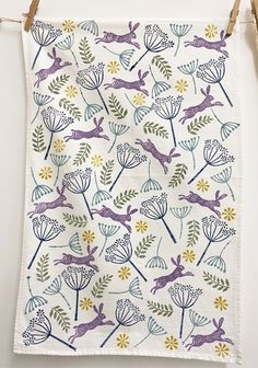 an embroidered tea towel hanging on a clothesline with flowers and deers in the background