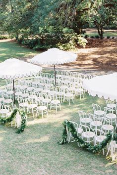 an outdoor wedding set up with white chairs and umbrellas