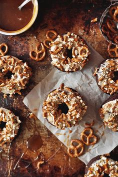 there are many donuts on the table with chocolate sauce and pretzel toppings