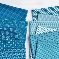 an assortment of blue and white fabrics with different designs on them, including flowers and circles