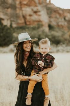 a woman holding a small child wearing a cowboy hat