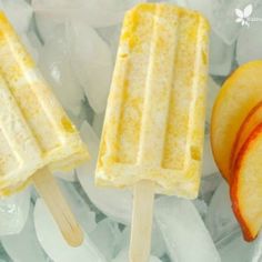 two popsicles with slices of apple on top of ice next to an orange slice