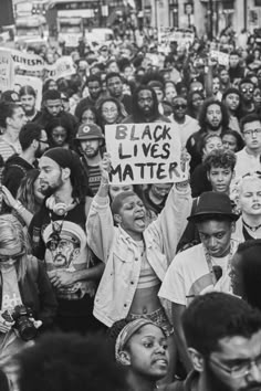 a large group of people holding signs and standing in front of each other on the street