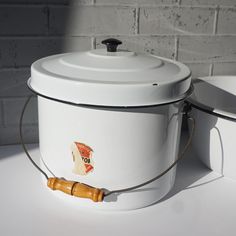 two white buckets sitting next to each other on a table with a brick wall in the background