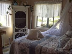 a bed sitting in a bedroom next to a window with sheer curtains on top of it