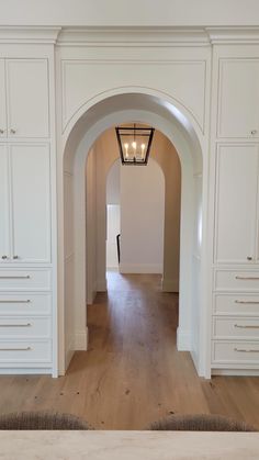 an archway leading to a bedroom with white cabinets and drawers on either side of the room