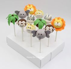 a bunch of cake pops with animals on them sitting on a white stand in front of a gray background