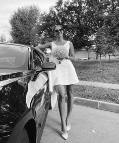 a woman standing next to a parked car