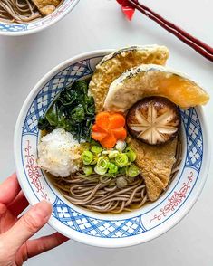 two bowls filled with different types of food on top of a white table next to chopsticks