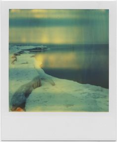 the polar bear is walking on the ice by the water's edge and looking at something in the distance