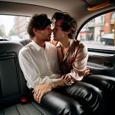 two young men sitting in the back seat of a car, one kissing the other