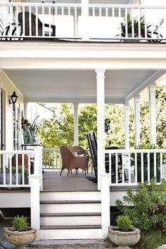 a porch with white railings and chairs on it