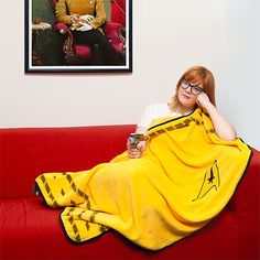 a woman sitting on a red couch with a yellow blanket