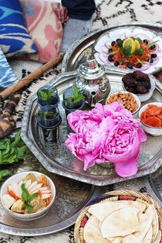 an assortment of food is displayed on a silver platter with pink flowers and other foods