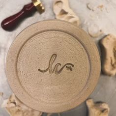 a close up of a ceramic bowl with a wooden handle on a table next to other items