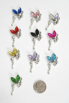 YOU ARE BIDDING ON 10 NEW RHINESTONE FAIRY/TINKERBELL"   CHARMS/PENDANTS.  YOU WILL RECEIVE A TOTAL OF 10- ONE OF EACH COLOR AS SHOWN.   THESE CHARMS ARE FROM A PET/SMOKE FREE HOME AND OH SO CUTE--I HAVE PUT A DIME IN THE PHOTO SO YOU CAN SEE THE SIZE OF EACH CHARM.  THESE ARE PERFECT FOR JEWELRY MAKING OR SCRAPBOOKING AND WHAT A GREAT PRICE.  THERE ARE NO JUMP RINGS WITH THESE CHARMS.   PROJECTS!  I WILL COMBINE SHIPPING--ONLY $.15 SHIPPING FOR EACH ADDITIONAL SET OF CHARMS PURCHASED.  ENJOY FR Whimsical Silver Dangle Charm Necklaces, Whimsical Silver Dangling Charms, Cute Silver Jewelry With Butterfly Charm, Silver Crystal Charm Necklaces For Jewelry Making, Whimsical Butterfly Charm Jewelry For Party, Whimsical Dangle Jewelry With Charms, Whimsical Party Jewelry With Butterfly Charm, Whimsical Jewelry With Dangling Charms For Party, Whimsical Silver Jewelry With Butterfly Charm