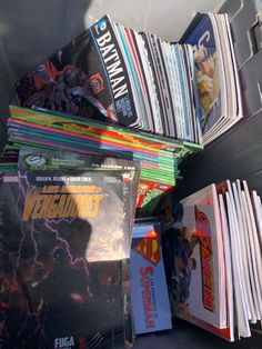 a bunch of comic books are stacked on top of each other in a bin together