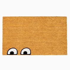 a yellow door mat with eyes drawn on the front and side, against a white background