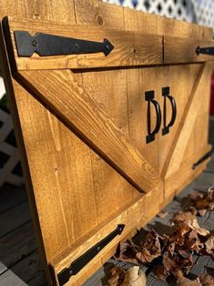 a close up of a wooden bench with leaves on the ground