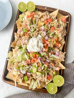 nachos with meat, lettuce and tomatoes on a tray