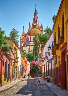 a narrow street with colorful buildings on both sides and a church in the back ground