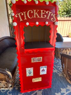 a red ticket machine sitting on top of a blue carpet next to a chair and table