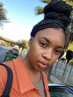 a woman with braids on her head standing in front of a car